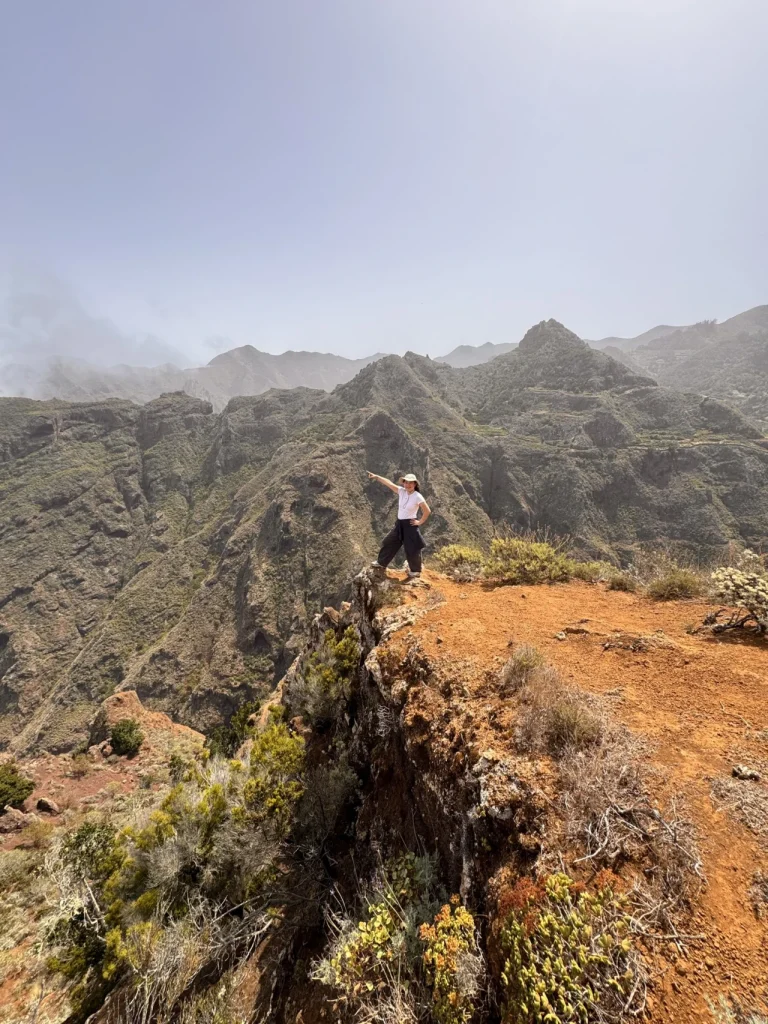 Senderista señalando el paisaje de Anaga mientras la niebla cubre las cumbres